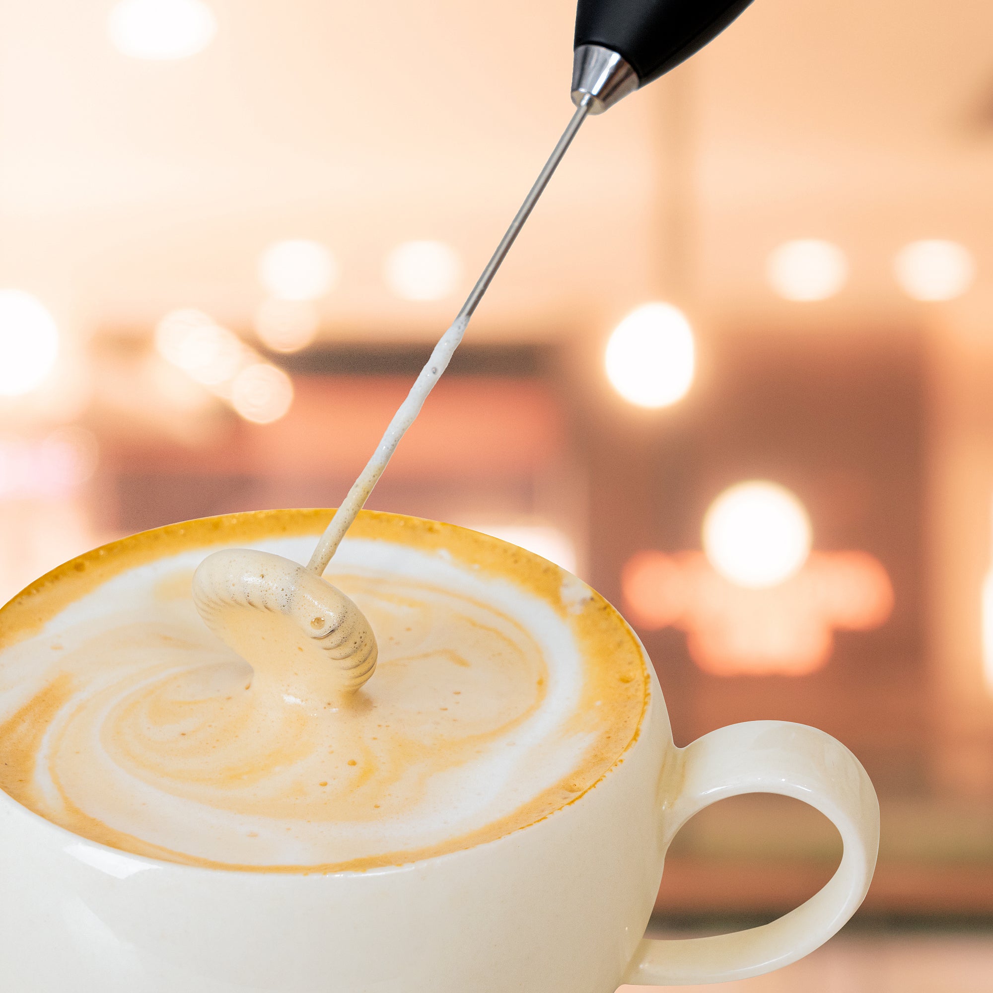 Foamo Melkopschuimer in gebruik, creëert romig melkschuim in een kop koffie.