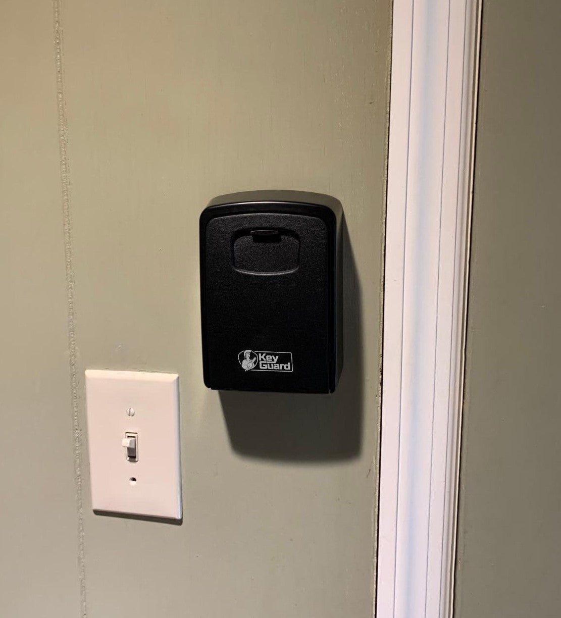 KeyGuard Sleutelkluis netjes bevestigd aan een binnenmuur naast een lichtschakelaar.